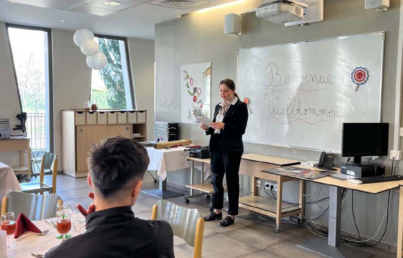 Die Azubis werden in einem Schulungsraum für Service von einer Lehrkraft begrüßt.