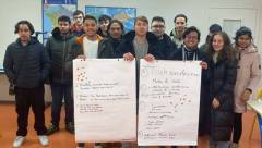 alle Teilnehmer posieren auf einem Gruppenfoto und halten im Vordergrund ihre erarbeiteten Plakate hoch